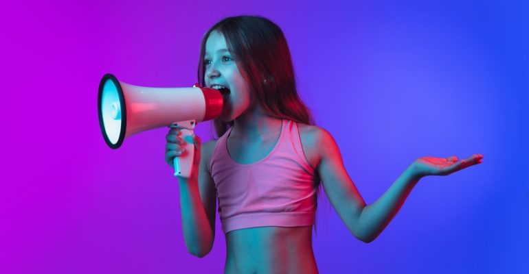 Little caucasian girl's portrait isolated on gradient pink-blue background in neon light.